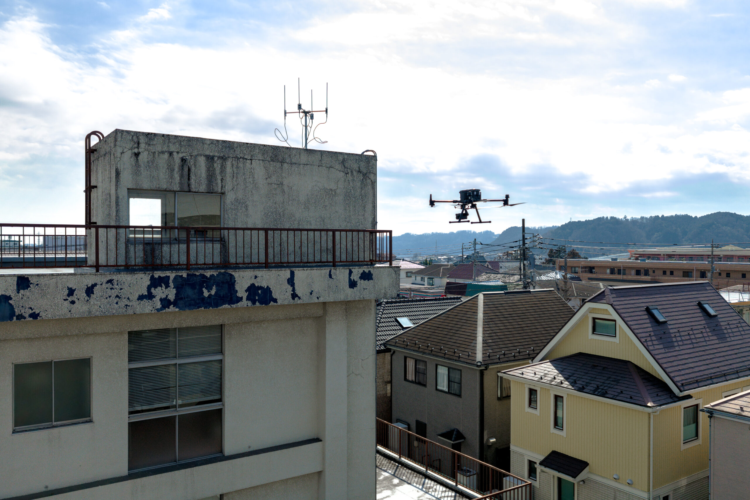 ドローンが建物付近を飛行している外壁調査現場写真